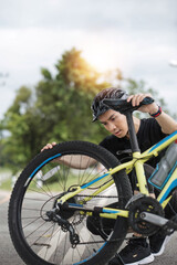 Fototapeta premium A professional young Asian male cyclist fixes his bike chain on the street after riding on country roads. maintenance, repair