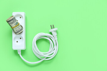 Power socket with dollar banknotes on green background