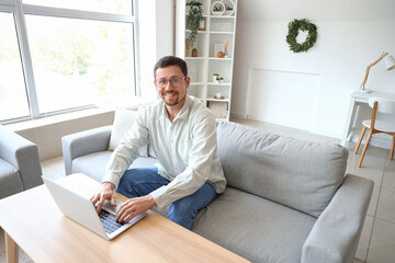 Handsome man in stylish eyeglasses using laptop at home