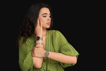 Obraz premium Beautiful young woman with wristwatches on black background