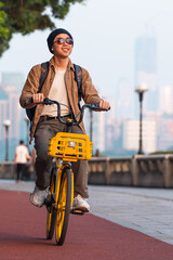 Asian man is riding a bike outdoor in the city. 