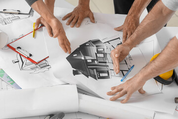 Team of male builders working with house plan in room, closeup