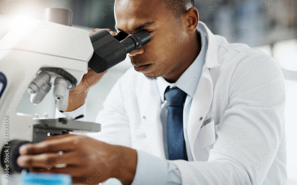 Aufkleber Looking closer...Cropped portrait of a handsome young male scientist using a microscope while doing research in his lab.