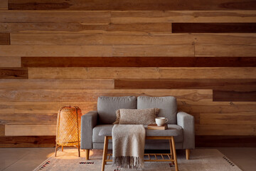 Glowing lamp, grey sofa and bench near wooden wall