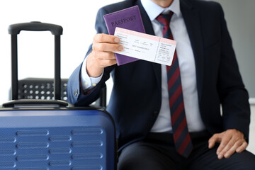 Mature businessman with ticket and passport in hall of airport, closeup
