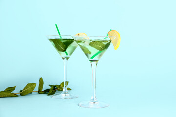 Glasses of tasty mojito on color background