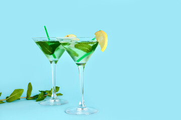 Glasses of tasty mojito on color background