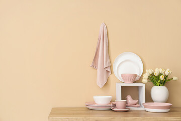 Set of clean dishes and vase with tulip flowers on wooden countertop