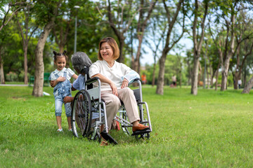 Fototapeta premium Portrait of happy love asian grandfather with grandmother and asian little cute girl enjoy relax in summer park.Young girl with their laughing grandparents smiling together.Family and togetherness
