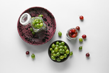Bowl and jars with fresh gooseberries on white background