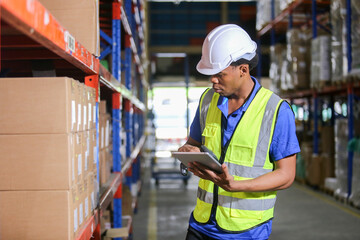 Man american african professional worker wearing safety uniform and hard hat using digital tablet inspect product on shelves in warehouse. Man worker check stock inspecting in storage logistic.