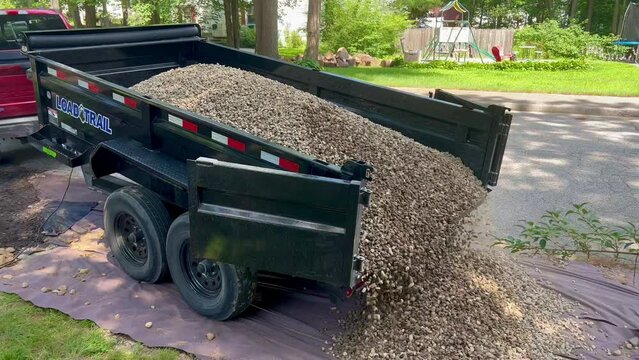 Truck dump trailer delivering crush stone to client.
