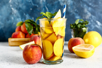 Glass of fresh peach lemonade with mint on white table