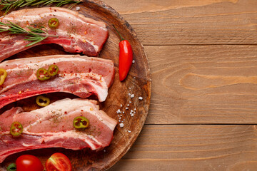 Plate with raw pork ribs and spices on wooden background, closeup
