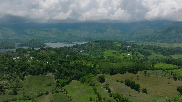 Farmland in mountain and lake surrounded by forest and jungle. Blue sky and clouds. Lake Sebu. Mindanao, Philippines.