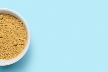 Bowl with ginger powder on blue background