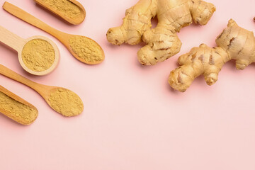 Fresh ginger roots, wooden spoons and scoops with dried powder on pink background