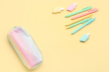 Pencil case with pens and markers on yellow background