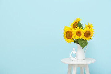Vase with beautiful sunflowers on table near blue wall in room