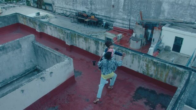 Romantic couple dancing Argentine tango on a rooftop in a poor district. High angle wide shot