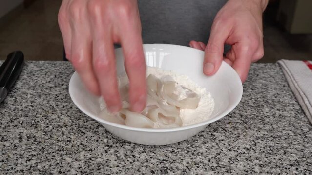 Hands Coating Uncooked Squid Rings With Flour Mix In A Bowl. closeup