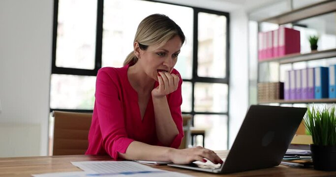Woman working in office with laptop looking tense and nervous with hands in mouth and biting nails. Problem of anxiety and neurotic