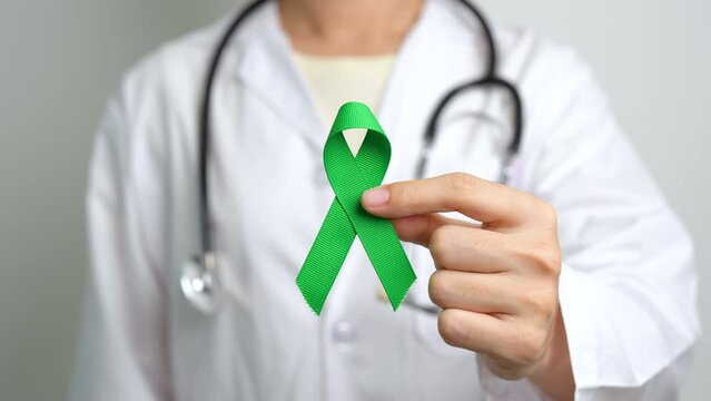 Doctor with green Ribbon for world Mental Health Day, Liver, Gallbladders, bile duct, cervical, kidney Cancer and Lymphoma Awareness month. Healthcare and world cancer day concept