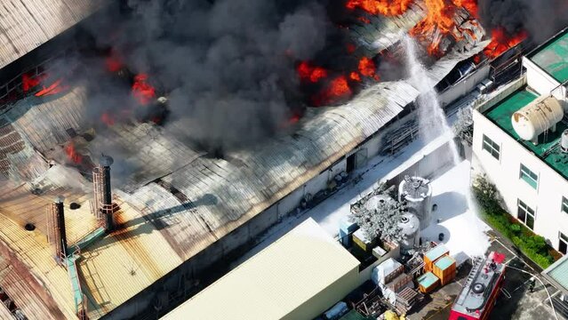 Aerial view of Fire in industrial building. Multi-storey concrete hangar with flames. 