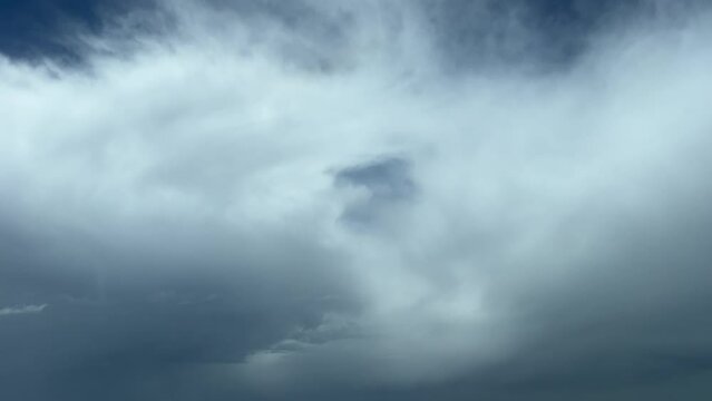 A pilot&rsquo;s perspective shot from a jet cabin while flying through some fluffy clouds with a deep blue sky at the back. 10000m high.