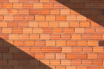 The old brown brick masonry wall background with sunlight and shadow on surface