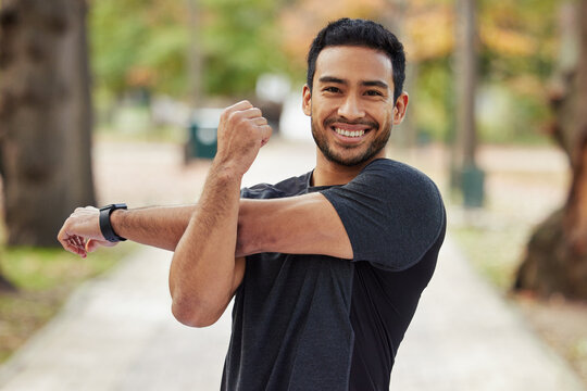 Happy asian man, portrait and stretching arms in fitness getting ready for running, workout or exercise at the park. Male person or runner with smile in warm up arm stretch, training or run in nature