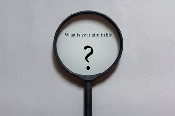 magnifying glass on gray background. What is your aim in life concept