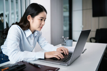 Asian Woman working by using a laptop computer Hands typing on keyboard. Working at office professional investor working new start up