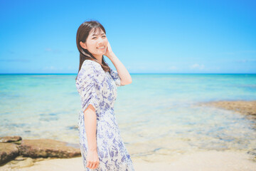 Fototapeta na wymiar 沖縄のビーチでバカンスを満喫するワンピースの女性