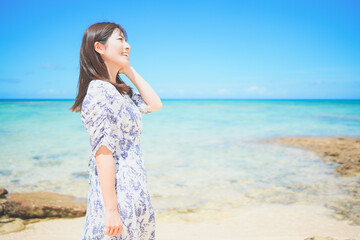 Fototapeta na wymiar 沖縄のビーチでバカンスを満喫するワンピースの女性