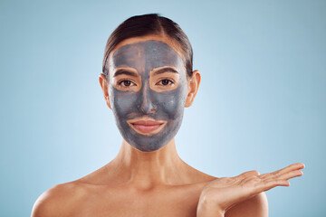 Face mask, skincare and beauty of woman showing facial product isolated in blue studio background. Skin, charcoal and person palm as advertising, branding or marketing hydration and clean dermatology