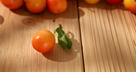 red cherry plum with a leaf on a wooden table. fresh fruits on a sunny day. veggie food. High quality photo.
