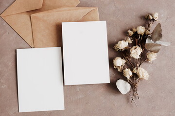 Card mockup, envelopes and dried flowers roses bouquet top view on beige textured background with copy space. flatlay. Blank, greeting card template.