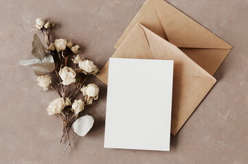 Card mockup, envelopes and dried flowers roses bouquet top view on beige textured background with copy space. flatlay. Blank, greeting card template.