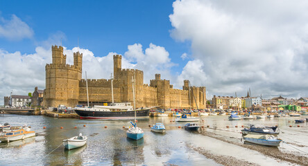 Caernarfon Castle on the River Seiont overlooking the Menai Strait in Wales - 627173378