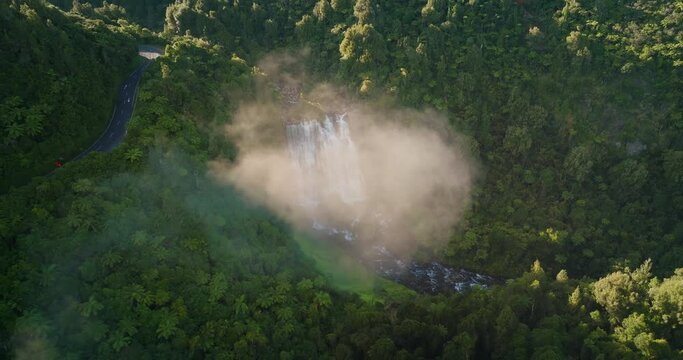 Soaring through cloud revealing Marokopa falls during sunrise, New Zealand