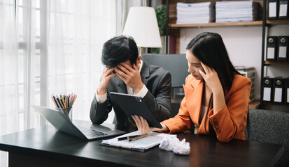 Furious two Asian businesspeople arguing strongly after making a mistake at work in modern office.