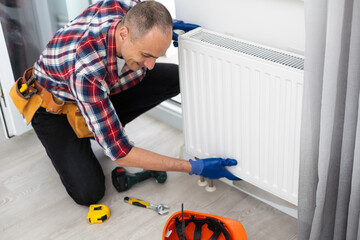 Repair heating radiator close-up. man repairing radiator with wrench. Removing air from the...