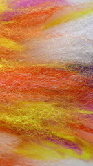 Vertical picture of fluffy wool-like threads in the colours orange, yellow, white and a bit of pink