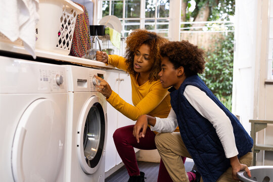 Happy african american mother and son doing laundry