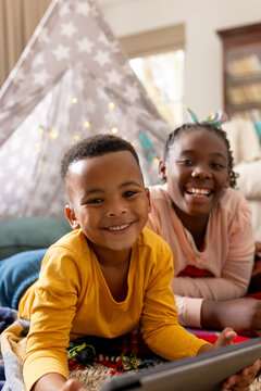 Portrait of happy african american brother and sister using tablet at home