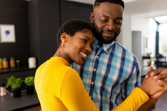 Happy african american couple dancing in kitchen at home