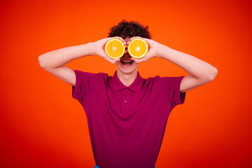 A young attractive guy with a good mood is posing in the studio with oranges.