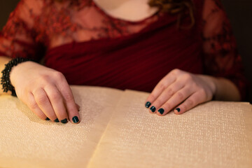 close-up of a woman's hand reading a braille book - obrazy, fototapety, plakaty