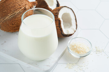 Glass of coconut milk and coconut close up on a white background with space for text. Coconut vegan milk non dairy or Dairy free milk concept. Healthy vegan food.